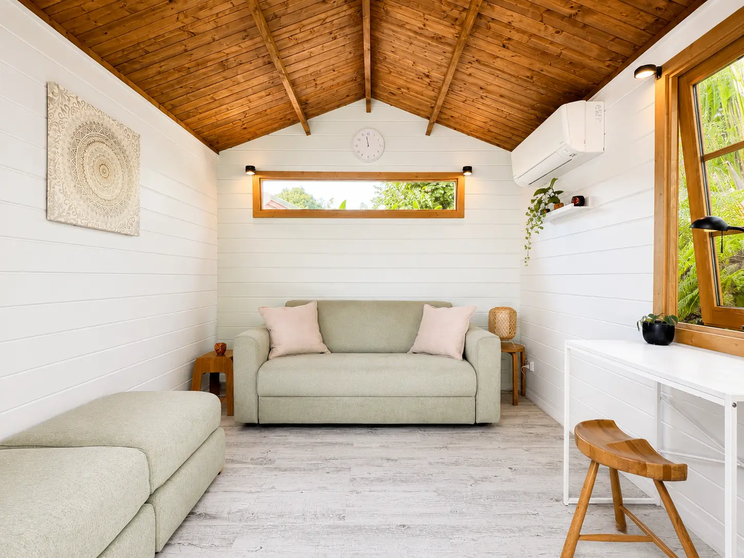 A light-filled consulting cabin with soft seating and a timber ceiling